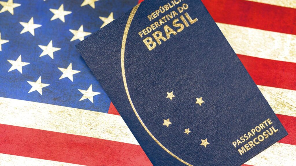 Passaporte brasileiro com bandeira dos Estados Unidos de fundo.